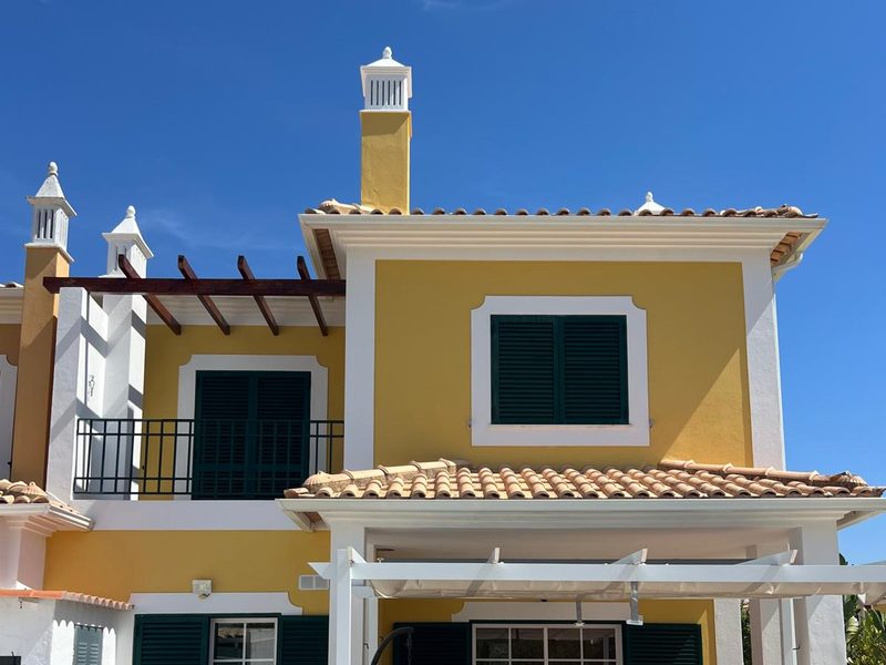 Rear elevation of a repainted villa in Algoz, Algarve, with chimneys and tiled canopy