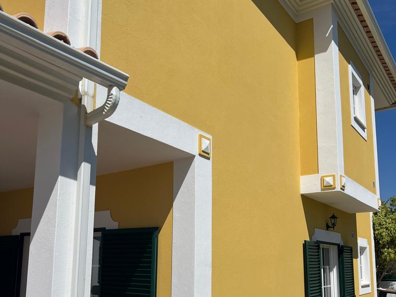 Corner detail of a repainted facade in Algoz: render, gutter and white trim