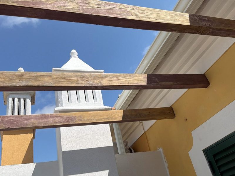 Weathered pergola beams before treatment, bleached grey by the Algarve sun